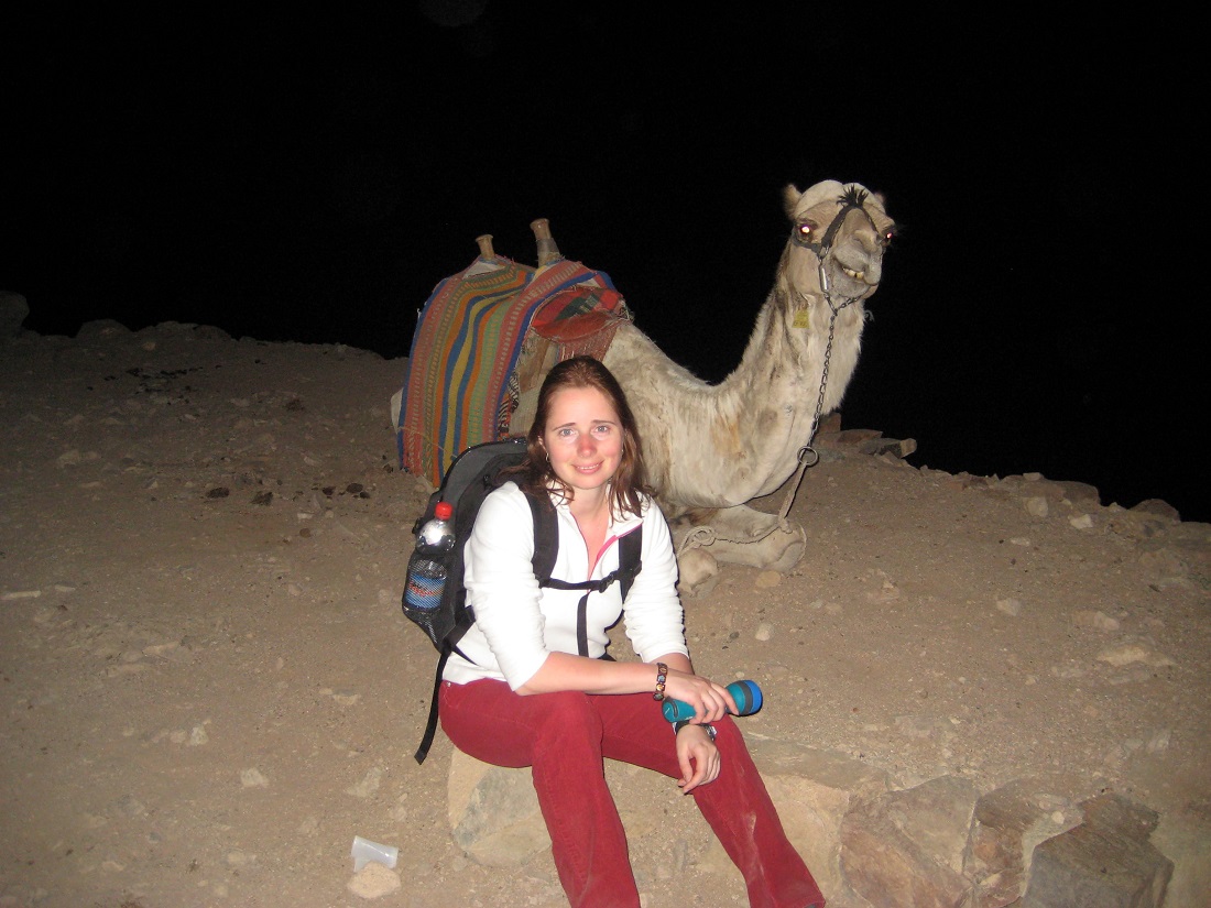 Elena crouching with a camel behind her